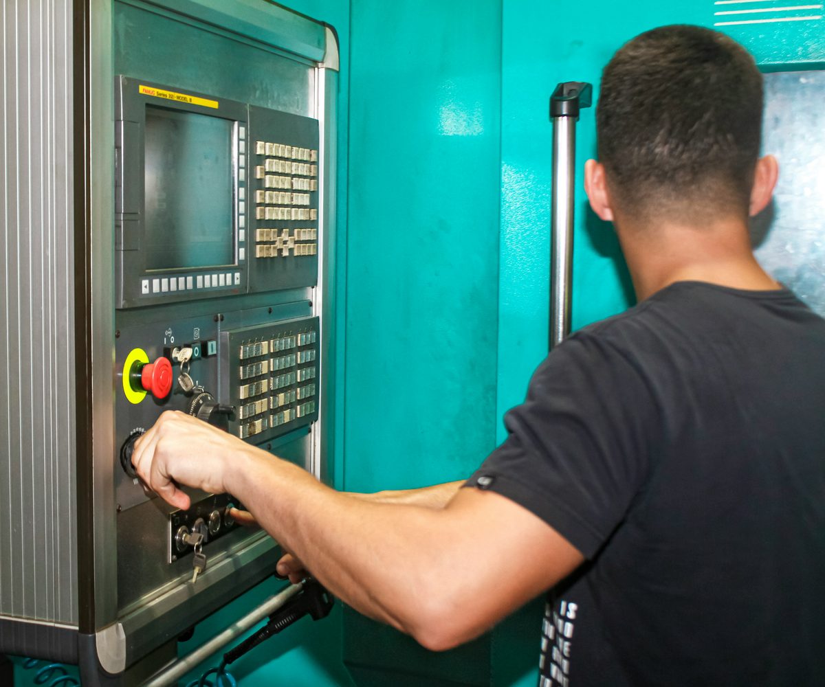 CNC-Fräser bedient das Steuerpult einer CNC-Fräsmaschine